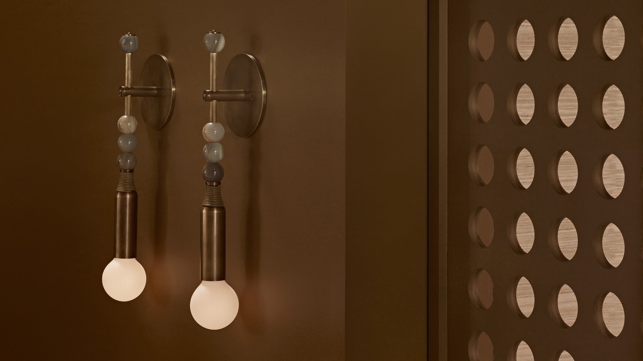 A pair of TALISMAN : 1 sconces in Aged Brass and Tan Leather with Agate stone mounted to a wall. 