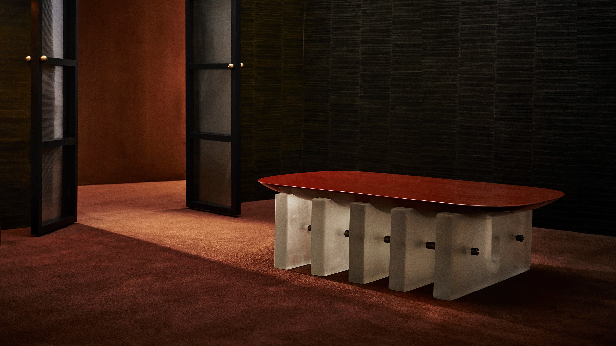 SEGMENT coffee table in Cinnabar Lacquer in a room with two open glass doors.