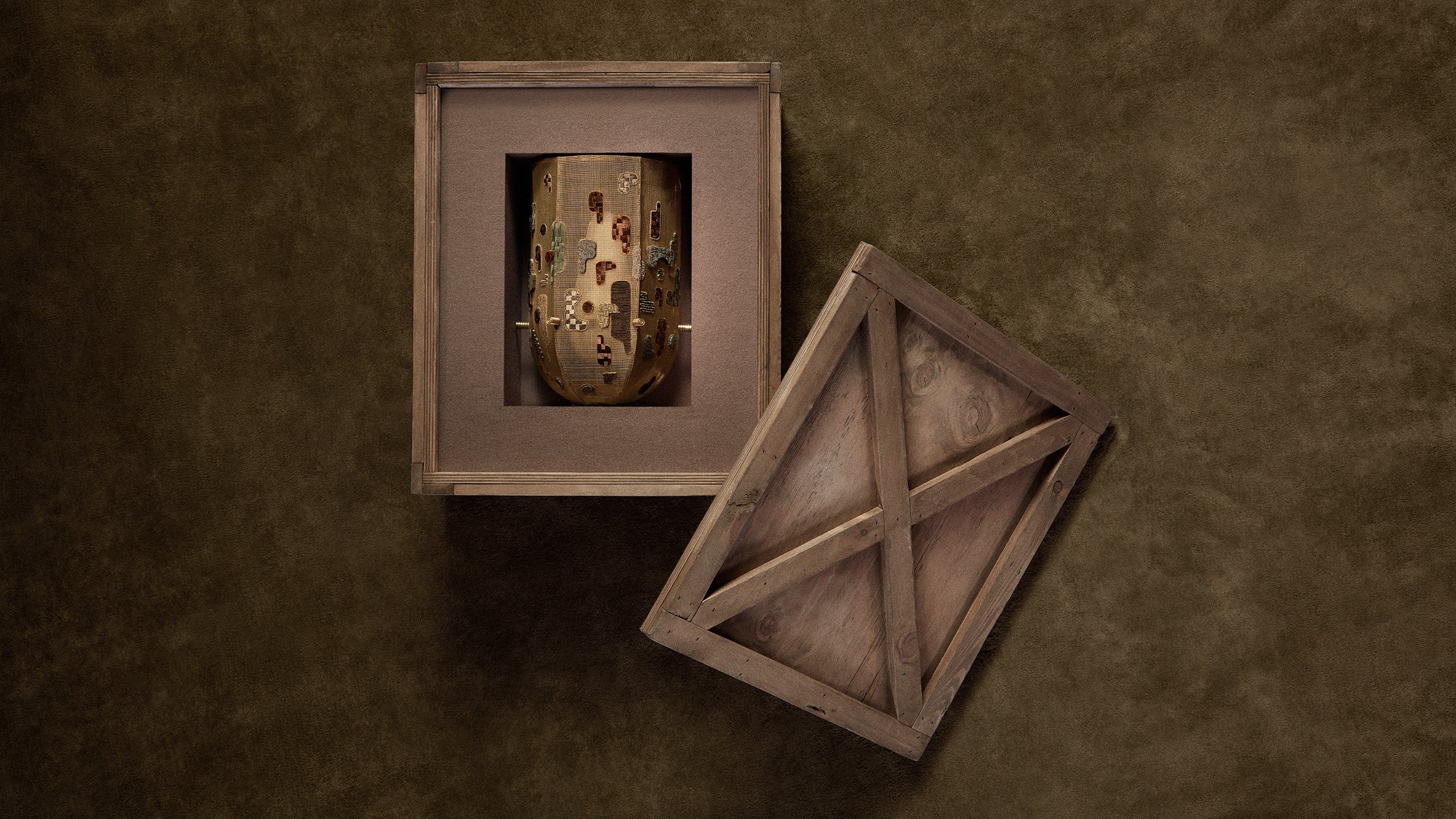 An open crate showing the INTERLUDE hand embroidered sconce inside. 