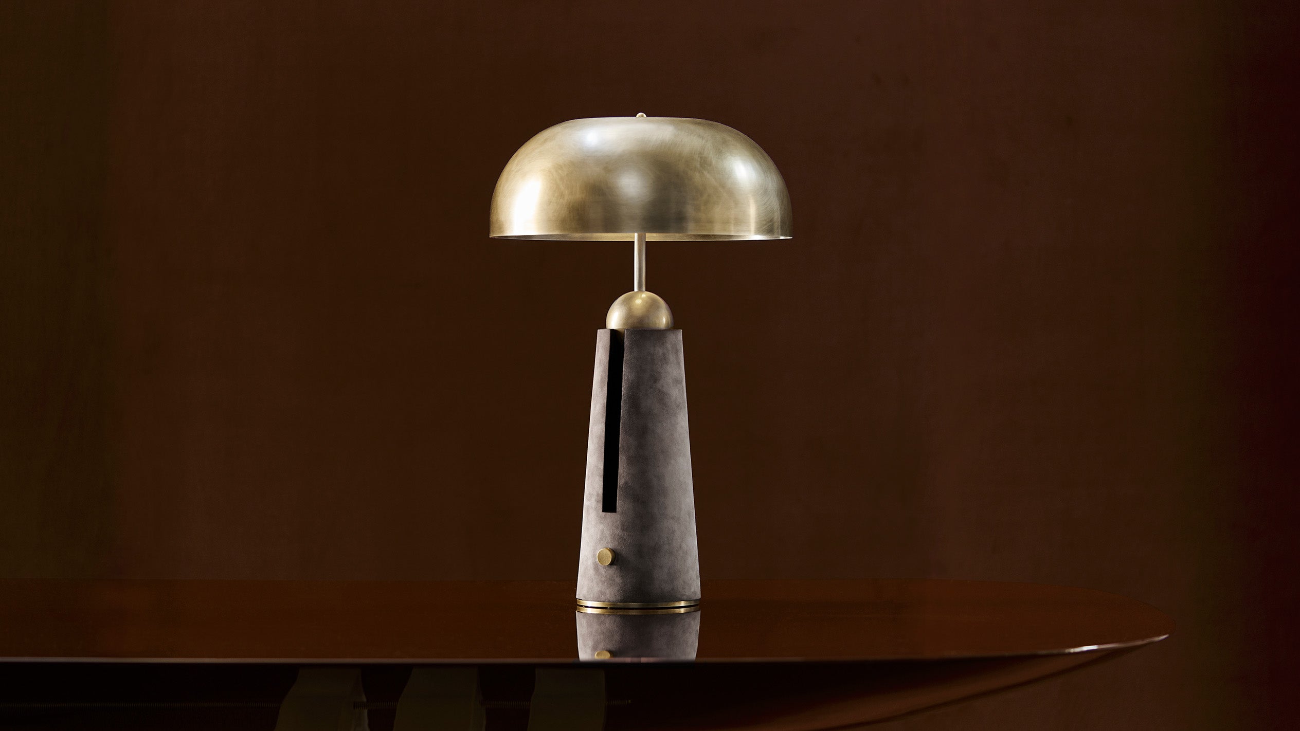 METRONOME table lamp in Aged Brass finish with Pewter Suede on a tabletop. 