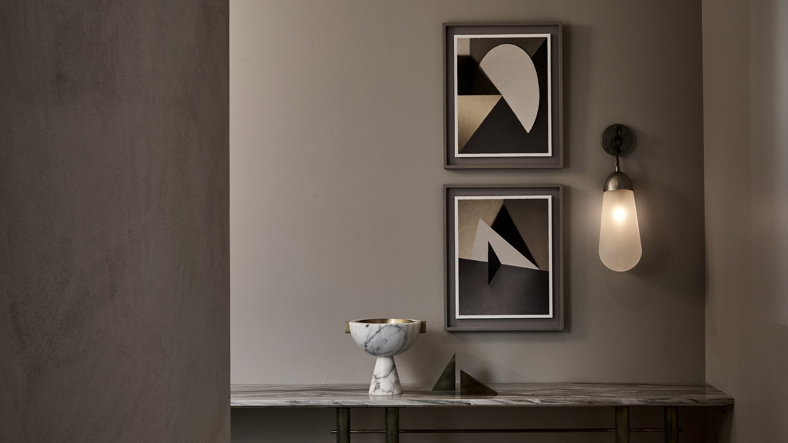 LARIAT wall sconce in Tarnished Silver finish mounted over a console table that's decorated with APPARATUS objects. 