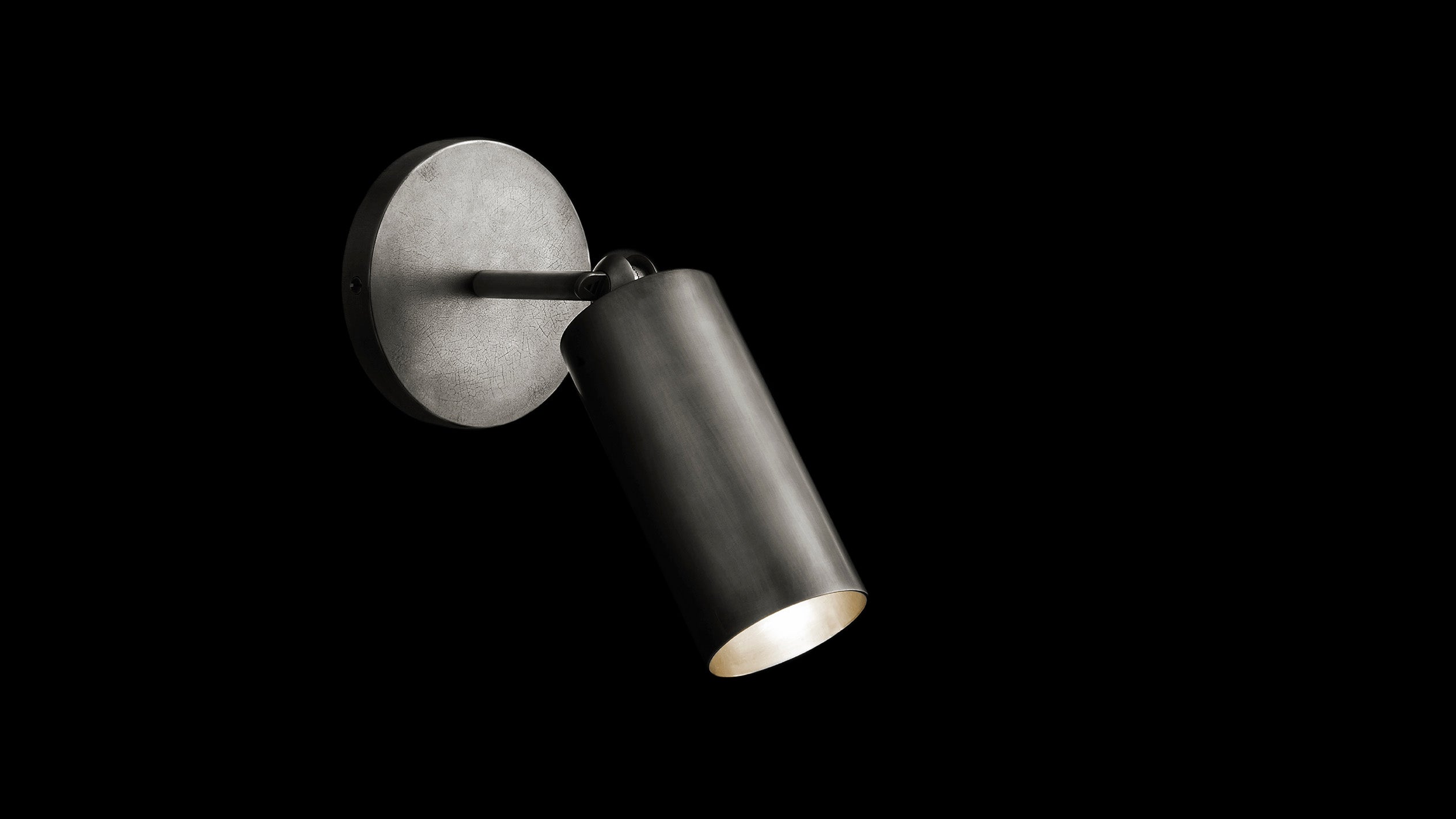 CYLINDER : SCONCE in Tarnished Silver finish, mounted to a black wall. 