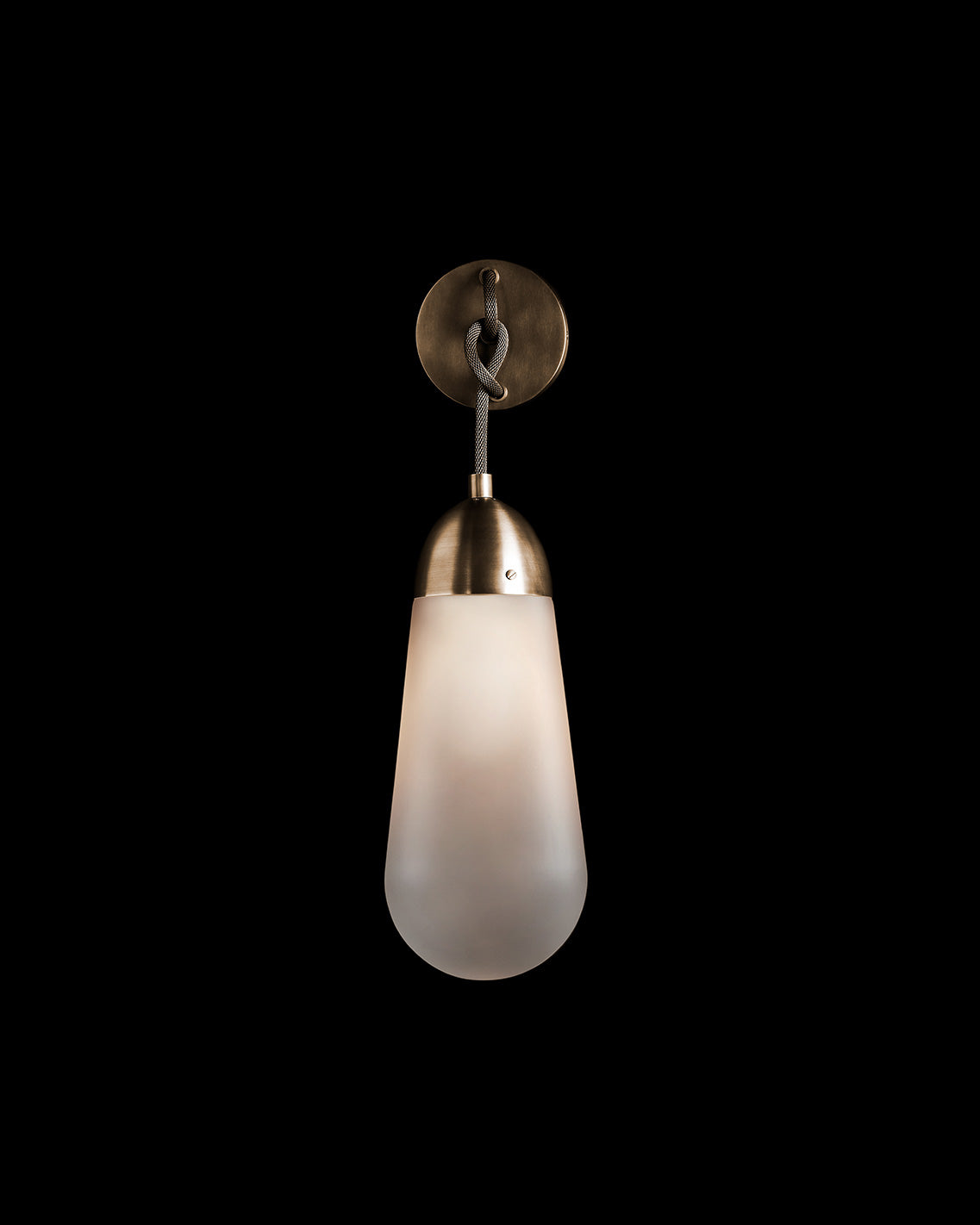 An illuminated LARIAT sconce mounted to a black wall. 