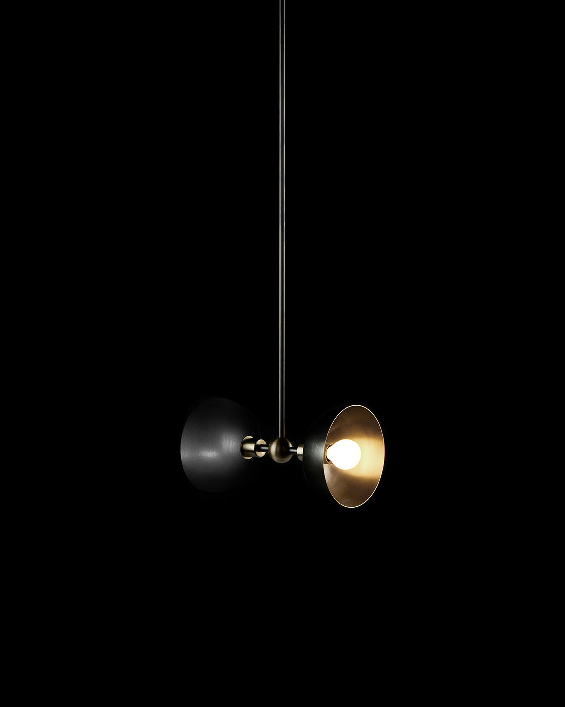 TRAPEZE : 2 ceiling pendant in Blackened Brass finish with Aged Brass bowls, hanging against a black background. 
