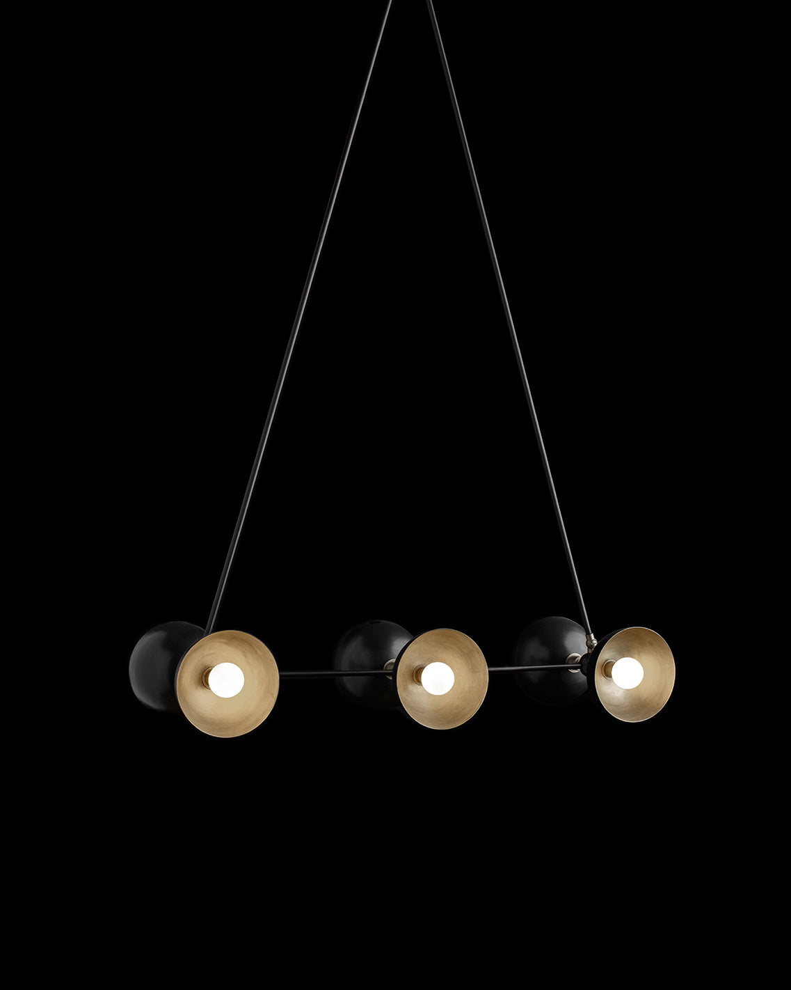 TRAPEZE : 6 ceiling pendant in Blackened Brass finish with Aged Brass bowls, hanging against a black background. 