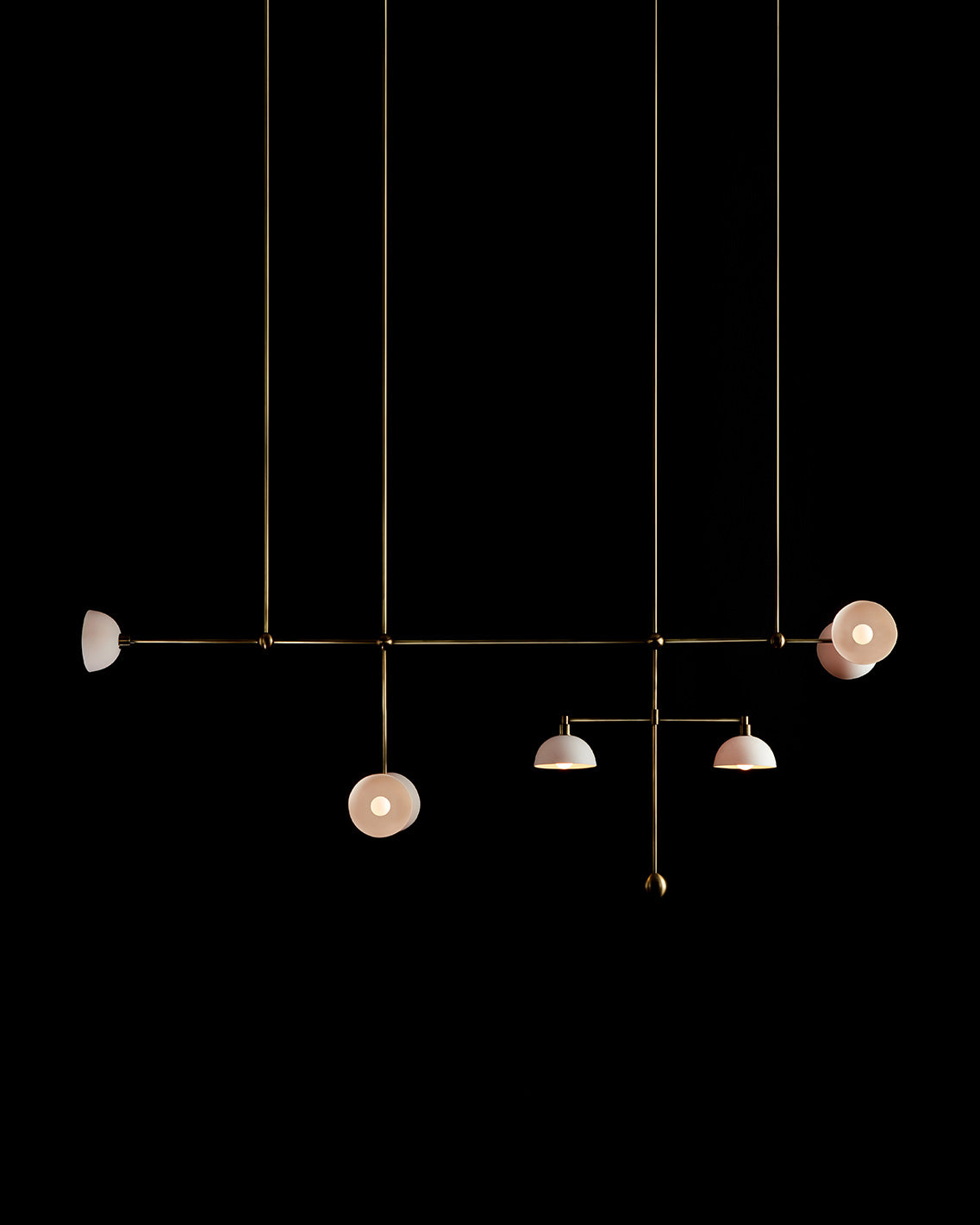 TRAPEZE : 7 MOBILE ceiling pendant in Aged Brass finish with Porcelain bowls, hanging against a black background. 