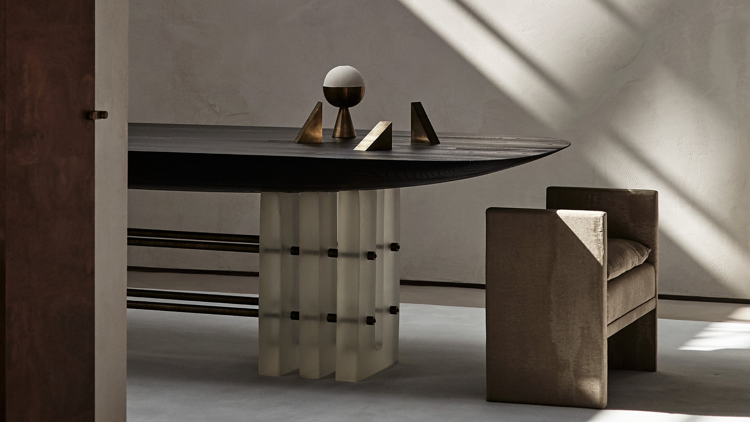 SEGMENT dining table in Blackened Ash Wood, decorated with an assortment of APPARATUS objects. 