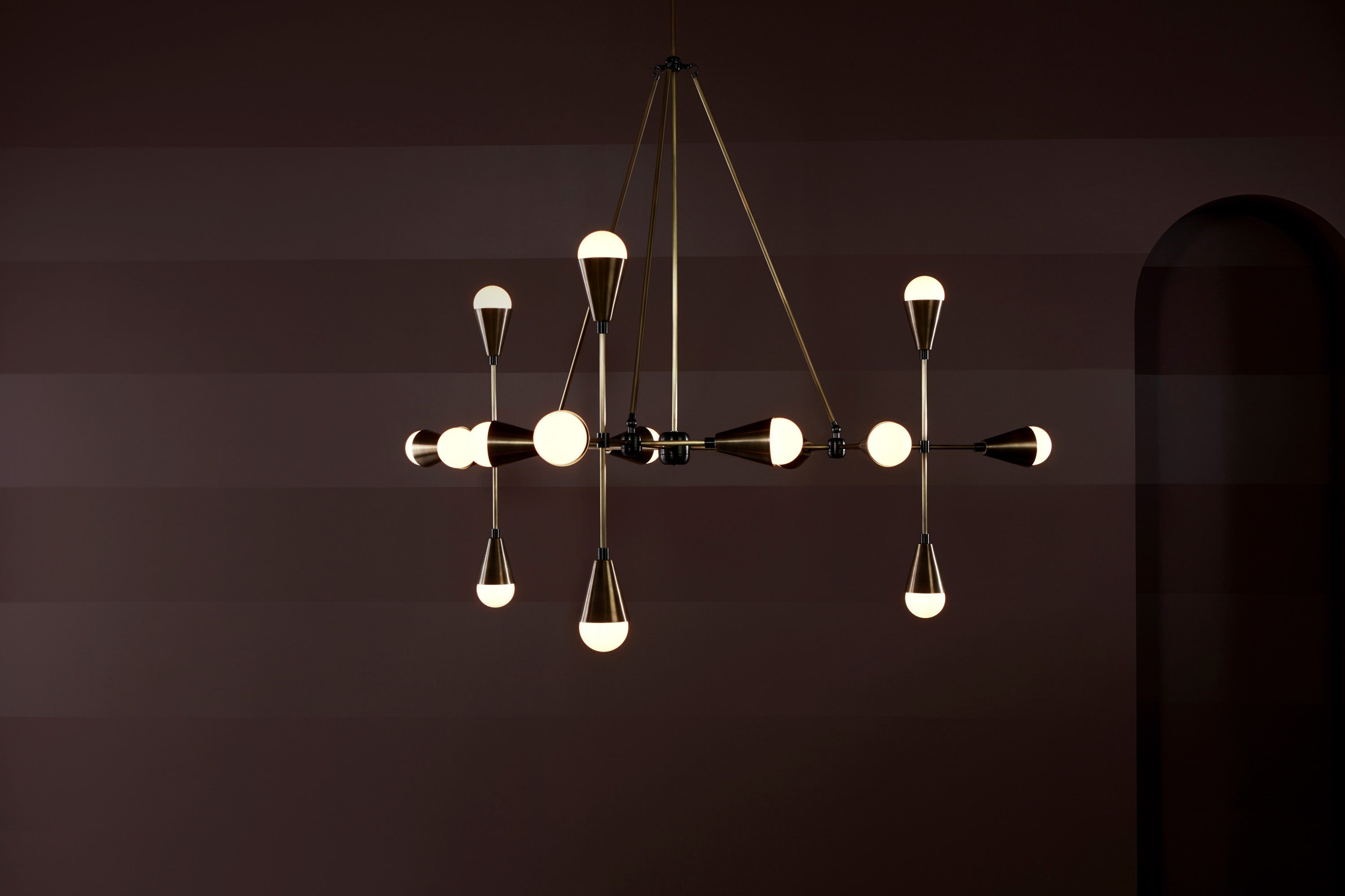 An illuminated TRIAD : 15 ceiling pendant in Aged Brass and Blackened Brass finish. 