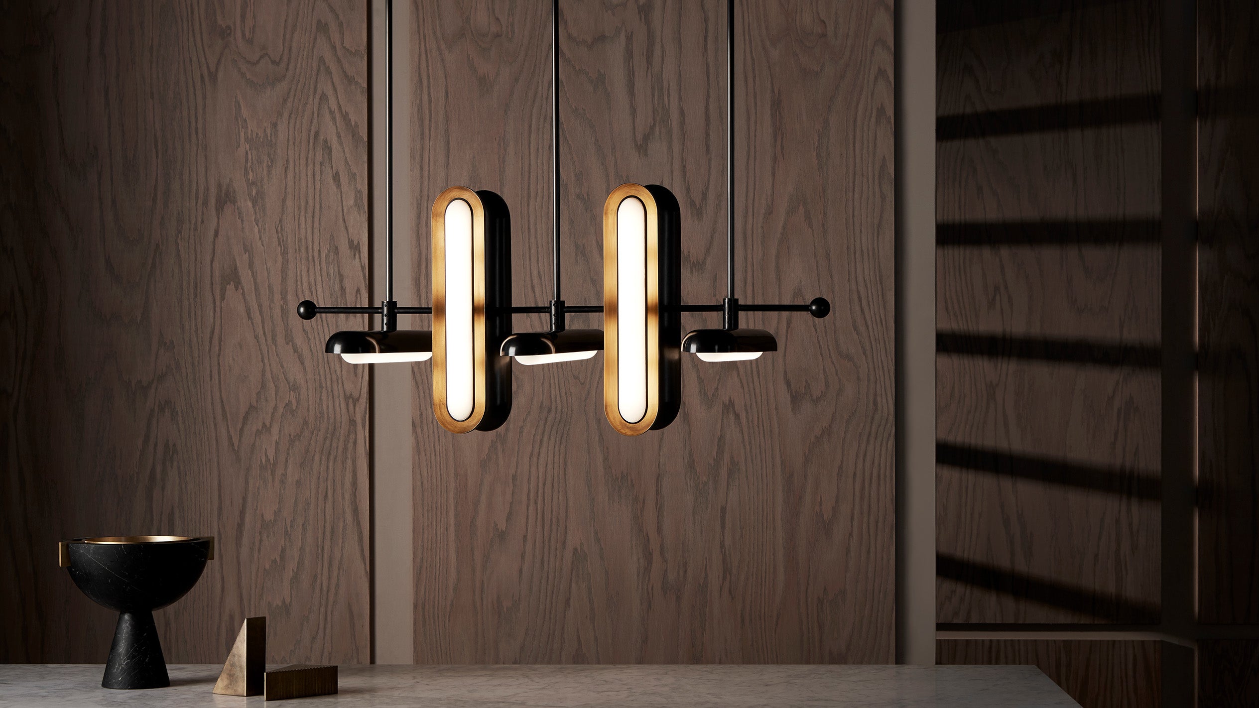 CIRCUIT : 7 ceiling pendant in two-tone finish, hanging above decorative objects on a table. 