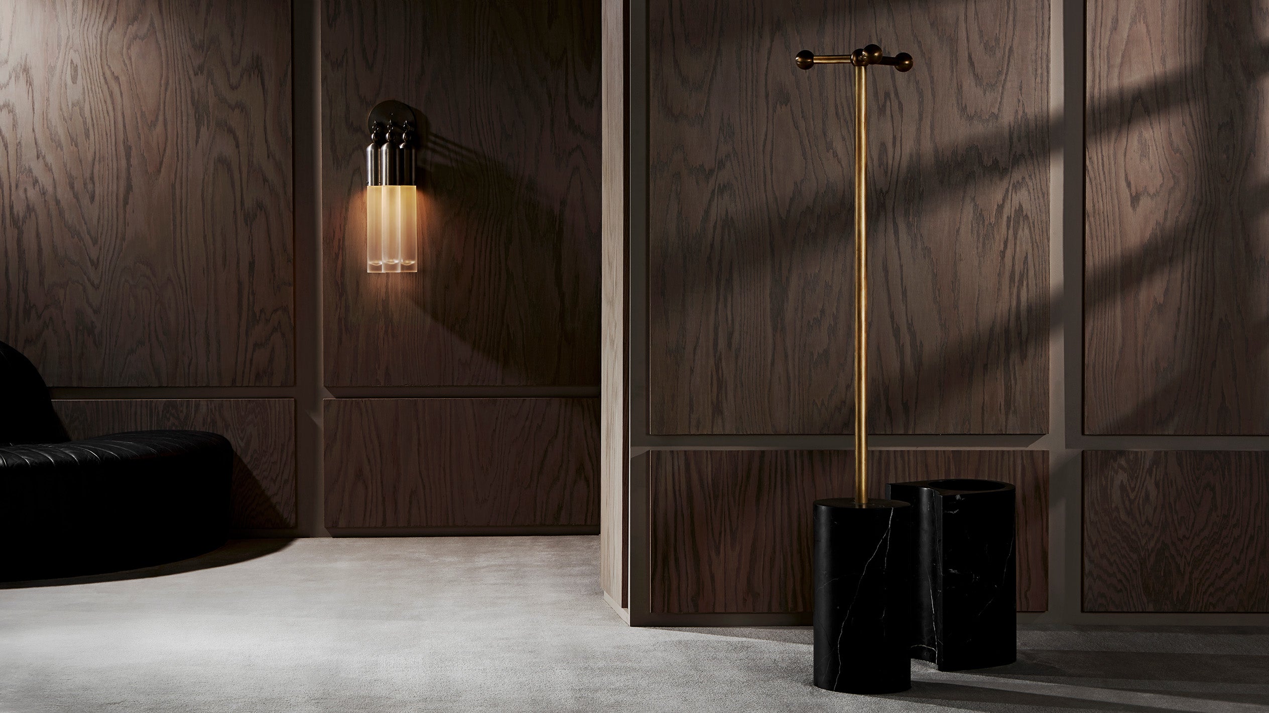 An illuminated TASSEL : 3 sconce mounted to a wood textured wall. 