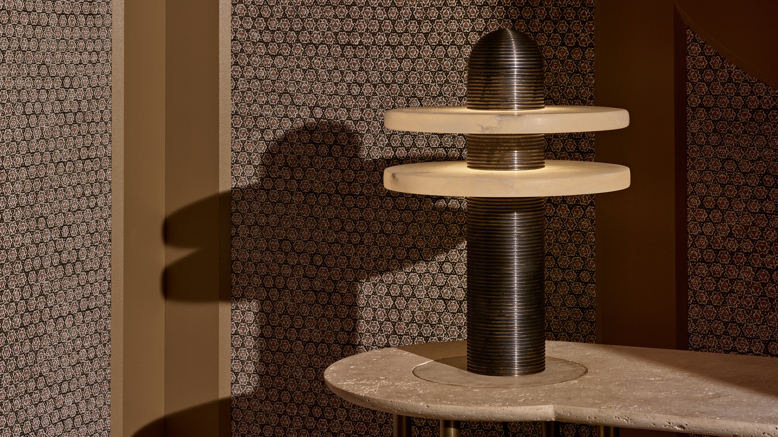 An illuminated MEDIAN table lamp on top of a PARS console table with Travertine stone. 
