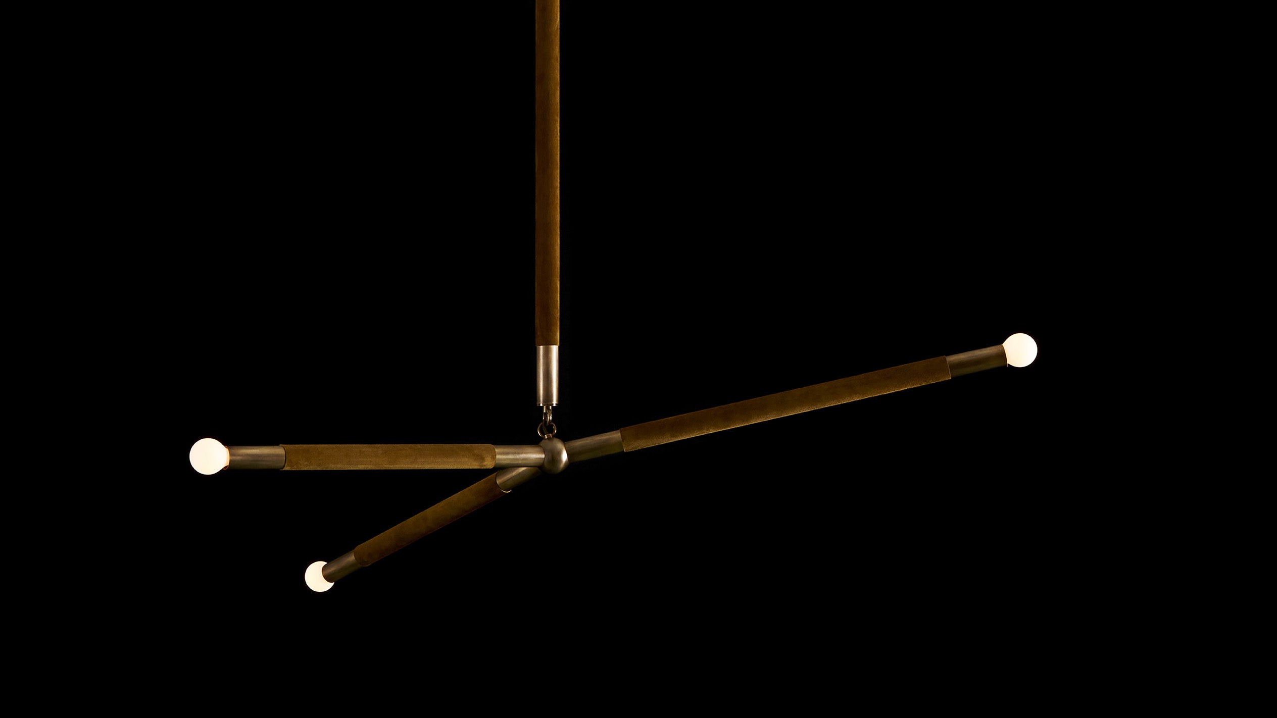 ARROW ceiling pendant in Aged Brass finish with Bronze Suede hanging against a black background.