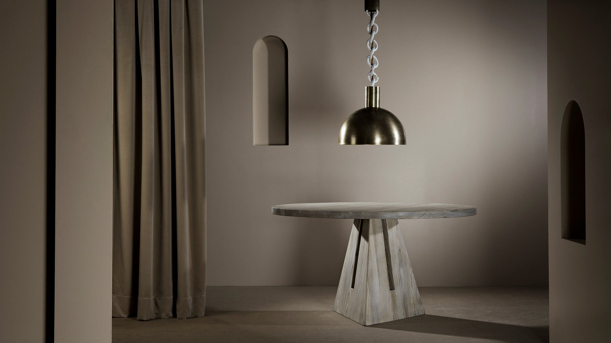 LINK ceiling pendant hanging over a circular PORTAL dining table in Bleached Ash Wood. 