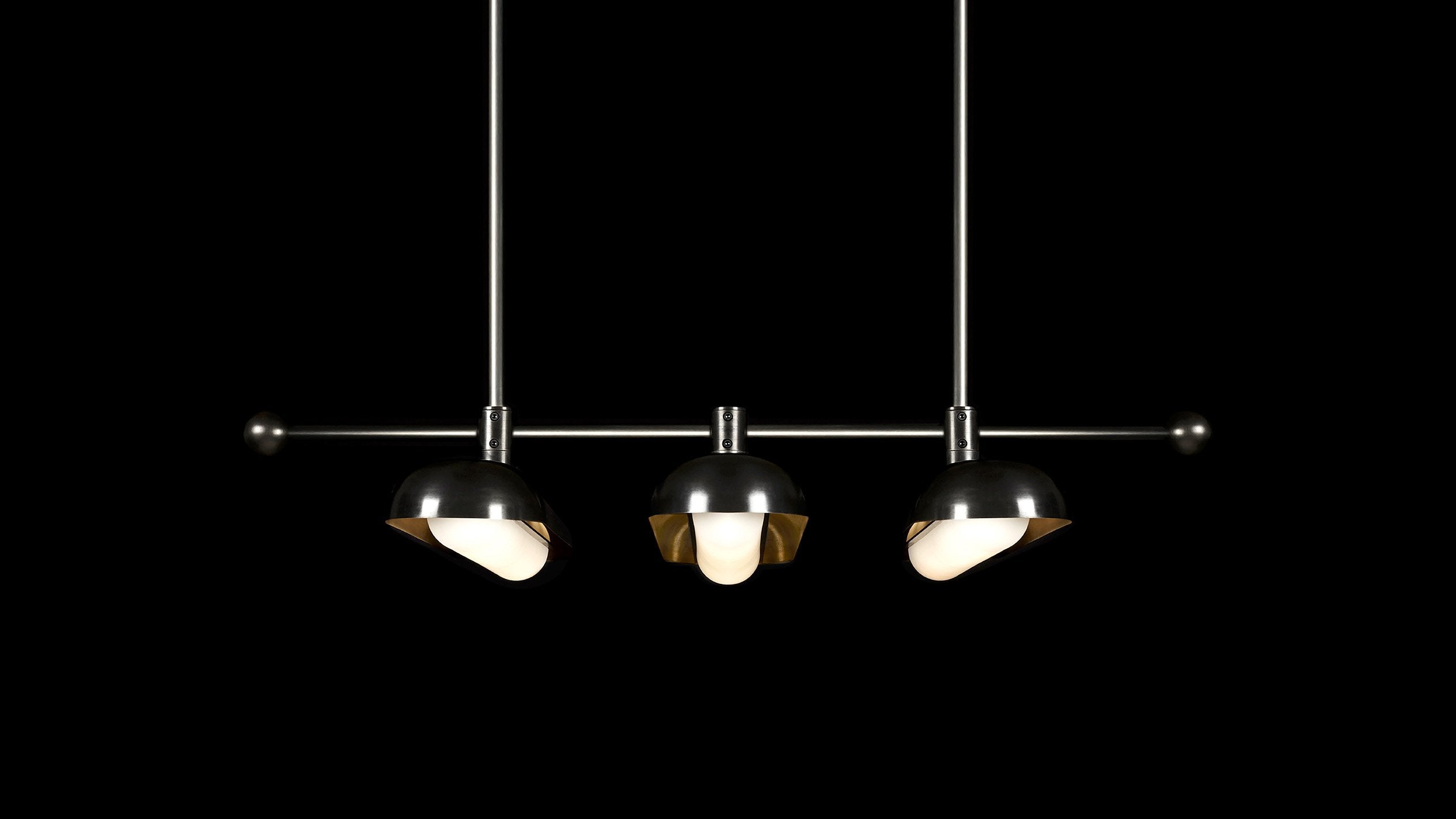 CIRCUIT : 3 ceiling pendant in a two-tone Blackened Brass / Aged Brass finish, hanging against a black background.