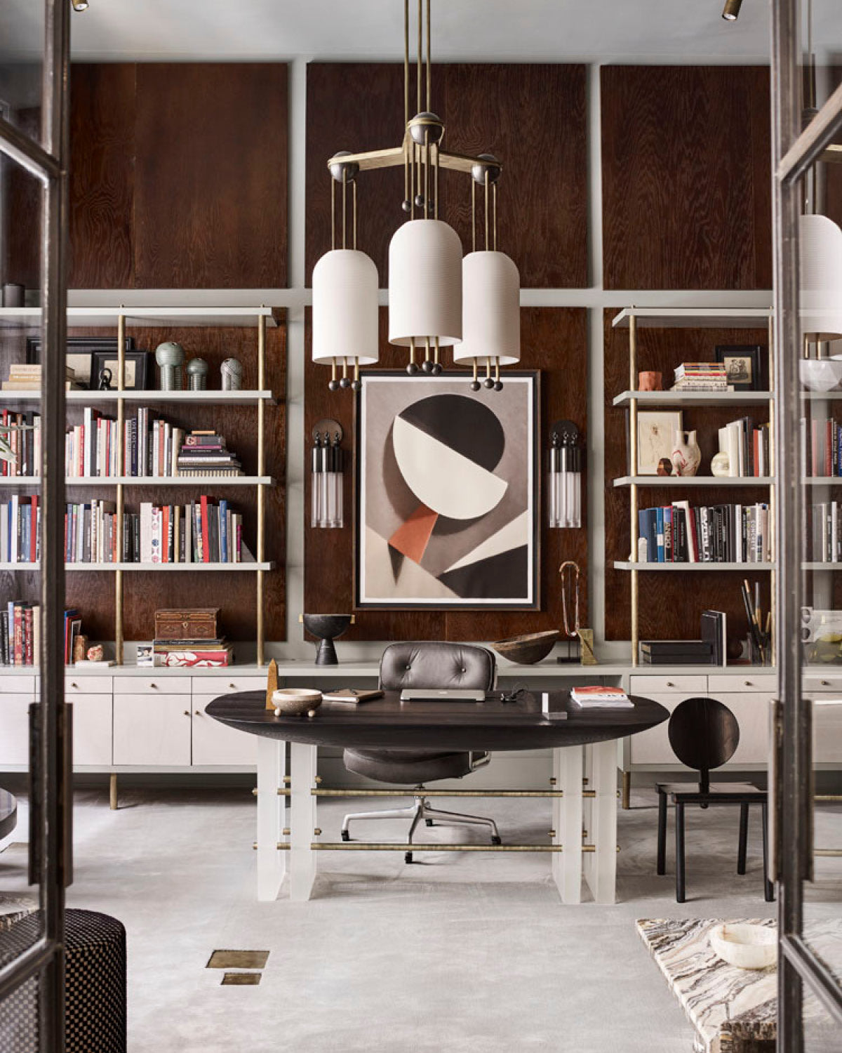 A LANTERN : 3 ceiling pendant hanging over a SEGMENT table with bookshelves in the background.