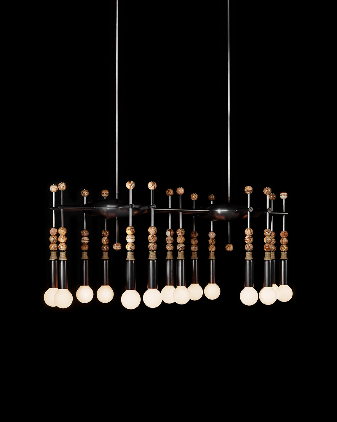 TALISMAN : 14 chandelier in Oil-Rubbed Bronze and Tan Leather with Desert Jasper stone, hanging in front of a black background. 