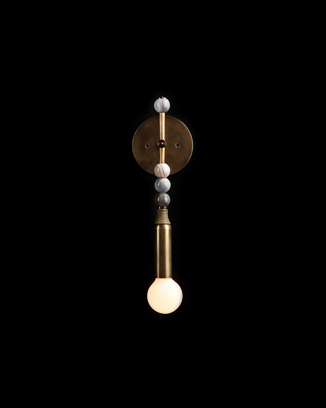 An illuminated TALISMAN : 1 sconce mounted to a black wall. 