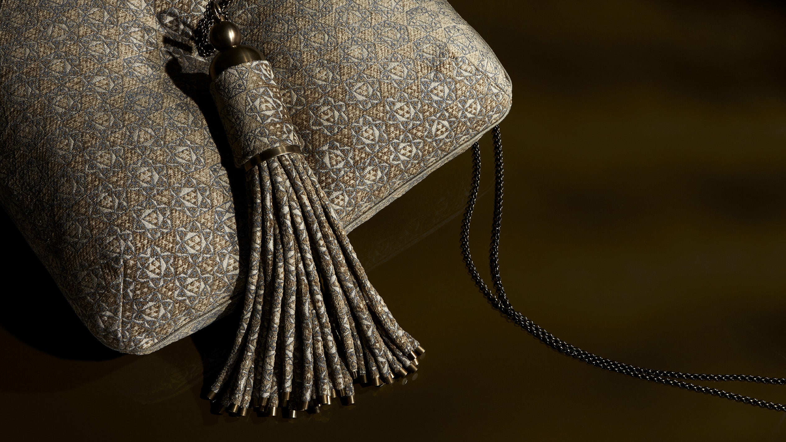 Close up of an upholstered cushion with a large tassel.