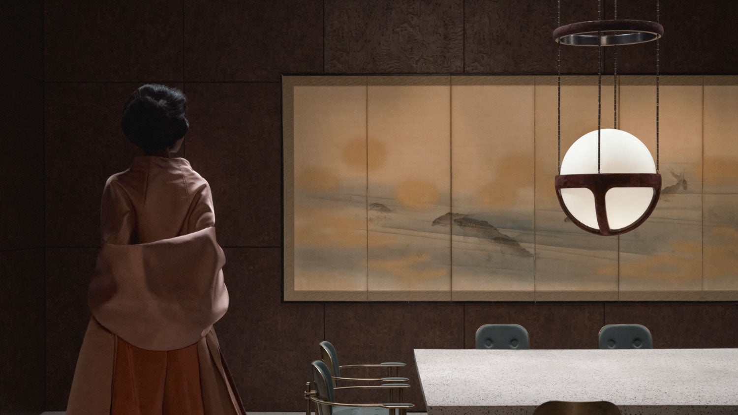 A woman is admiring a painting that is hanging behind a REPRISE ceiling pendant. 