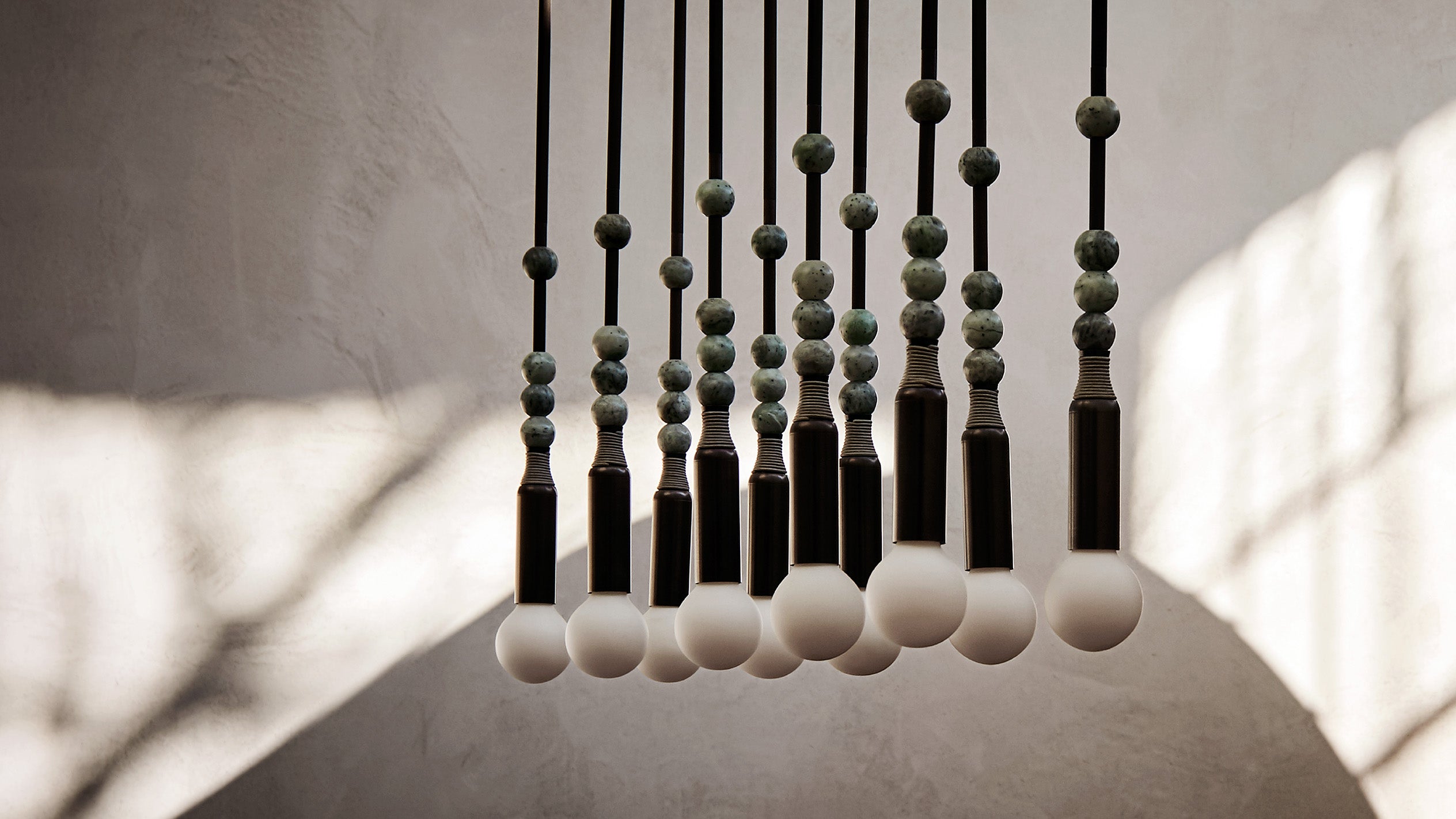 Ten TALISMAN : 1 ceiling pendants in Oil-Rubbed Bronze, Jade stone and Cool Gray Leather hanging at different heights. 