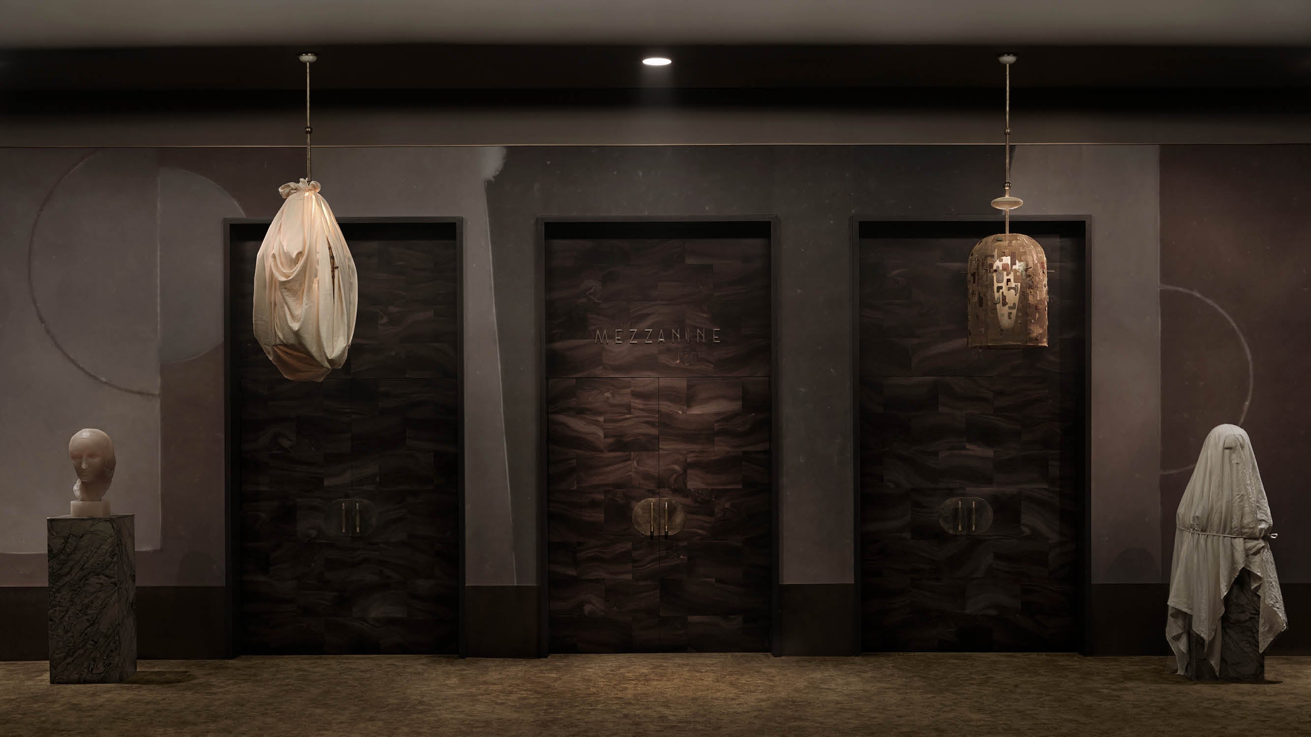 A pair of INTERLUDE hand-embroidered ceiling pendants, one covered with a cloth and the other uncovered, hanging in front of 3 doors. 