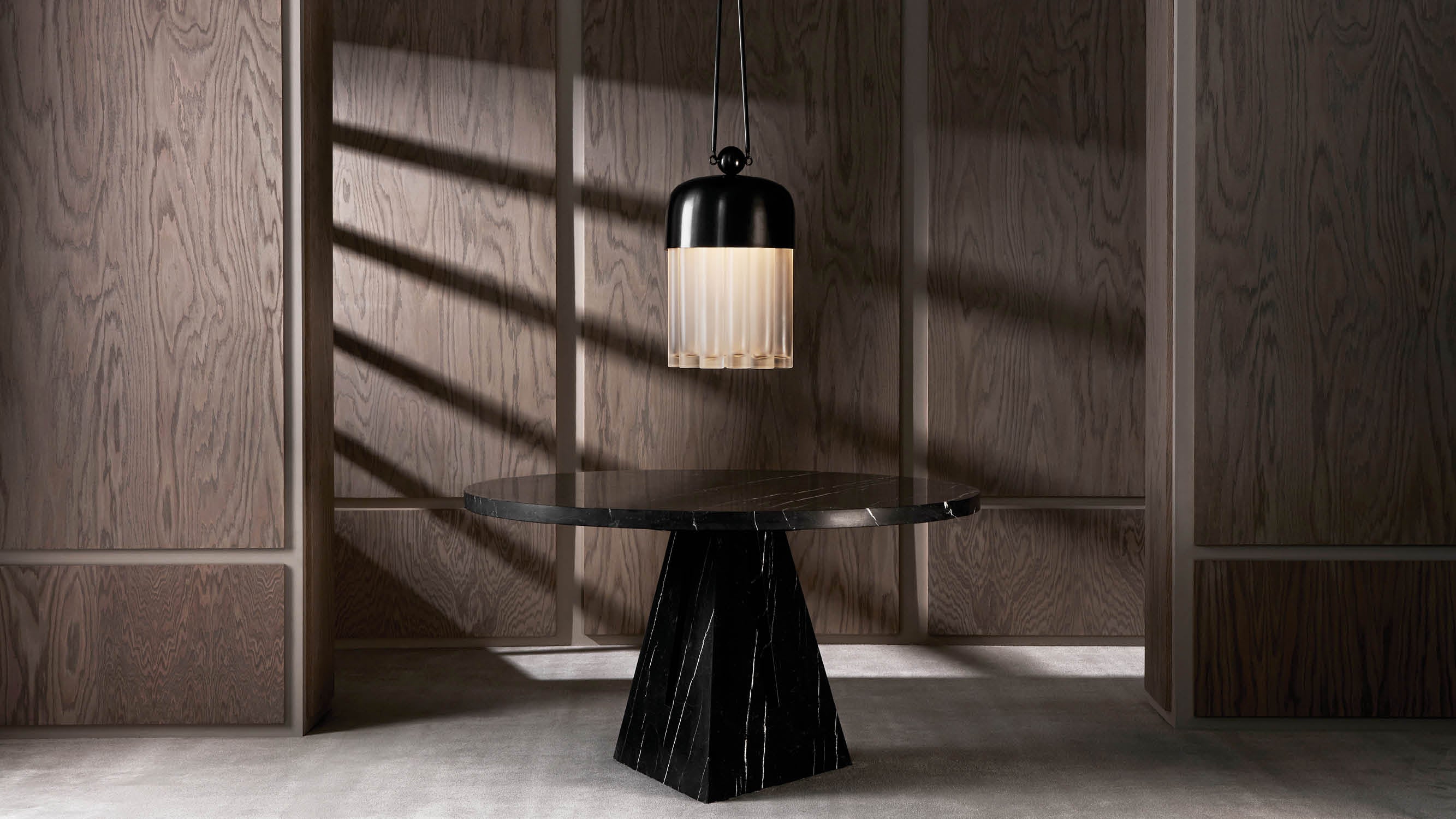 An illuminated TASSEL : 19 ceiling pendant hanging above a circular PORTAL dining table.