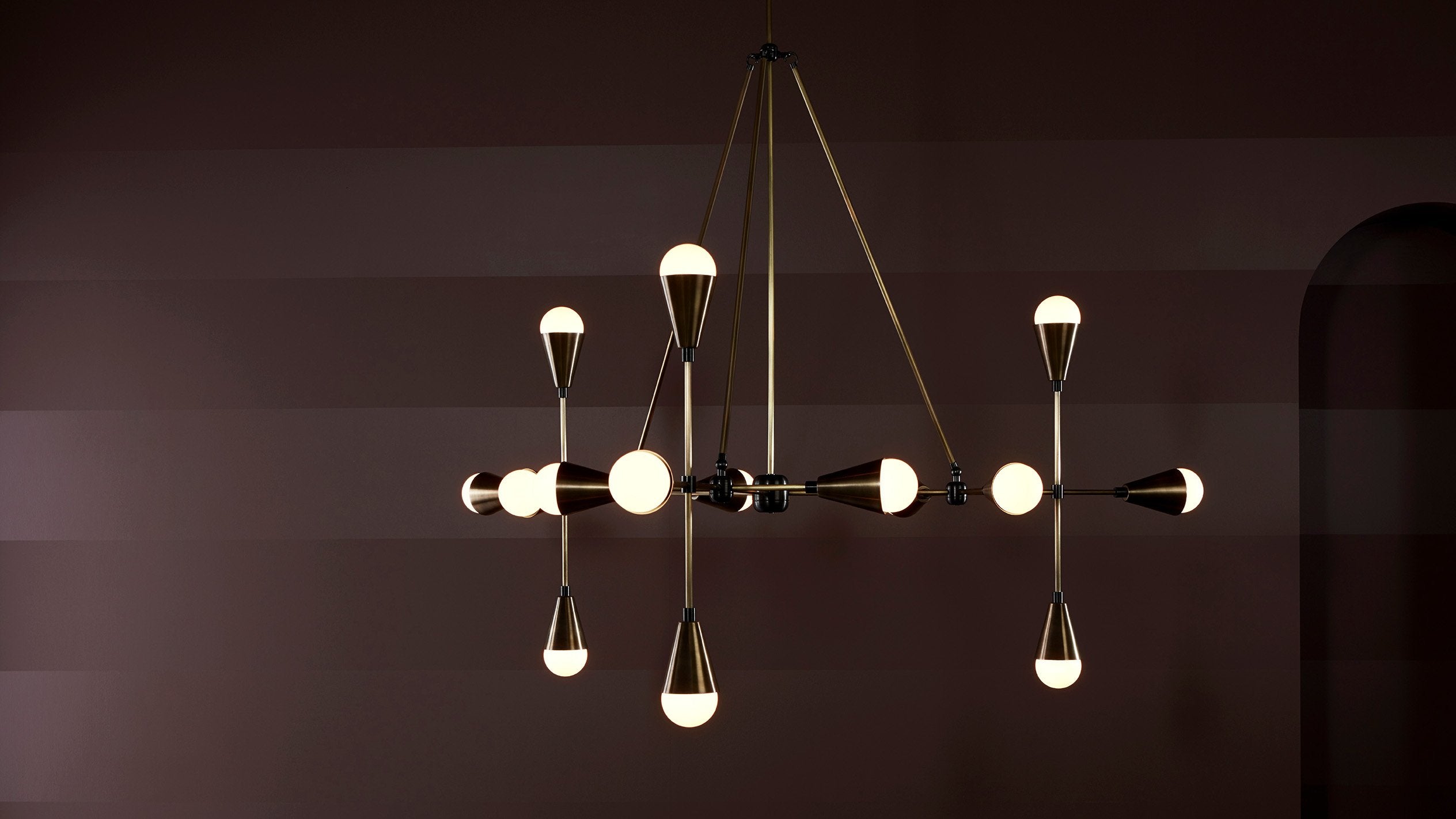 An illuminated TRIAD : 15 ceiling pendant in Aged Brass and Blackened Brass finish. 