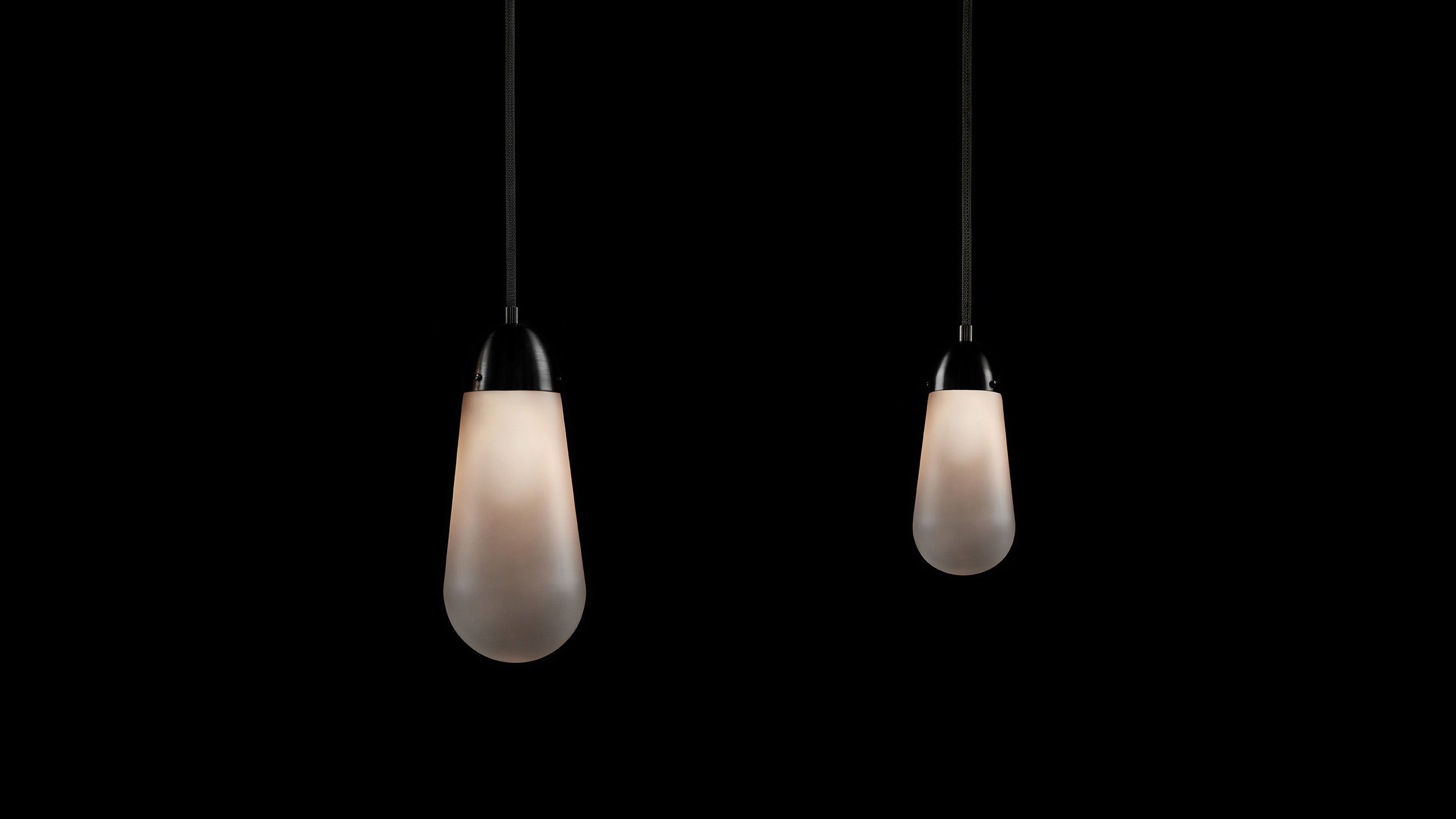 Large LARIAT ceiling pendant hanging next to a small LARIAT ceiling pendant against a black background. 