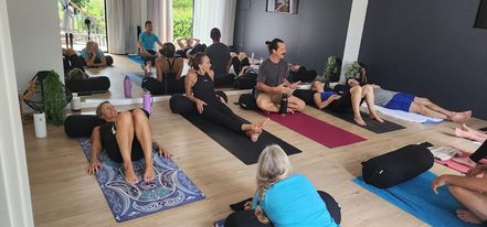 Wim Hof facilitator explaining the breath work method sitting in front of a group of people lying and sitting on yoga mats