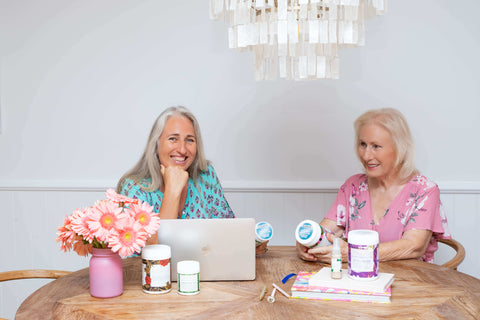 Mayella CoFounders Amanda and Robyn at a desk with open laptop holding and discussing Mayella Products