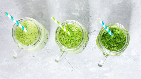 three variously coloured green juices in mason jars