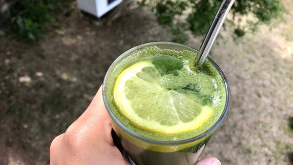 Green C juice in a glass with a metal straw