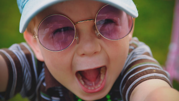 close up image of an excited toddler with retro purple glasses