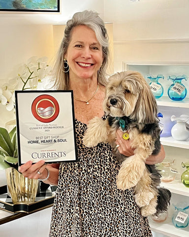 Photo of Lori Savio, Owner of Home, Heart & Soul, holding her dog and a framed LKN Currents Award for Best Gift Shop