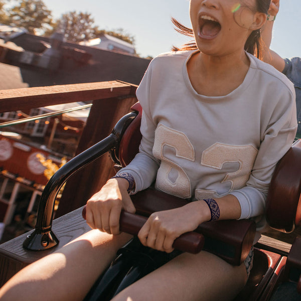 Woman on roller coaster wearing Blisslets nausea relief bands for motion sickness