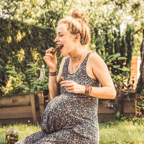 Pregnant woman eating a pickle with Blisslets morning sickness bands