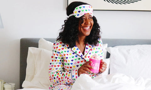 Kalyn Chandler of effie's paper sitting in bed smiling and holding a pink cup of coffee