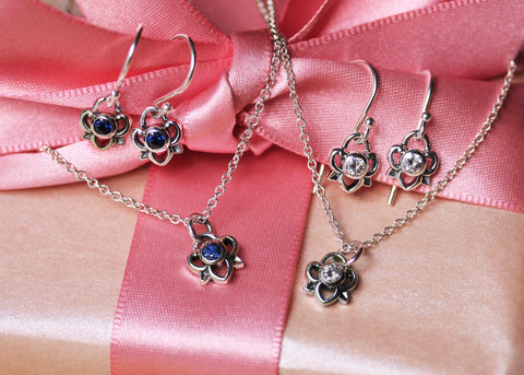 sapphire and moissanite earrings and pendants on a gift box with a pink bow
