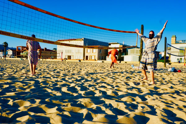 men playing beach volleyball wearing robes as swim cover ups