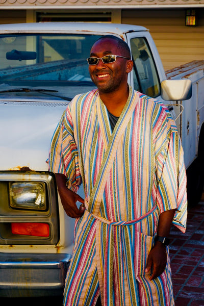 man posing next to truck weairng robe as swim cover up