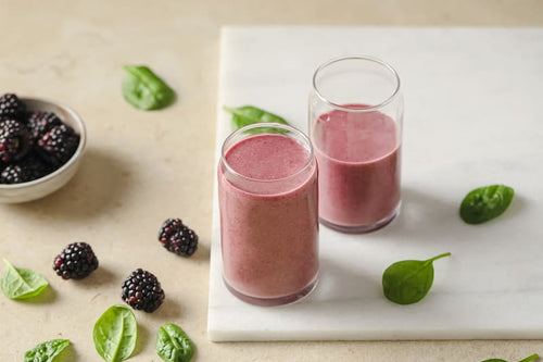 PACK'D smoothies in two glasses, sat on a chopping board