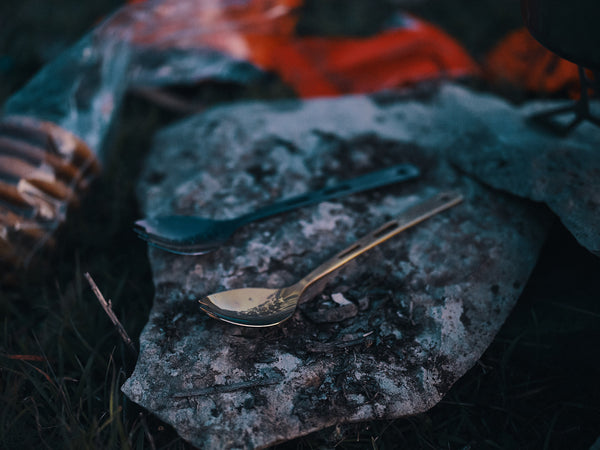 Two titanium spoons sitting on top of a rock