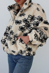 girl wearing cream sherpa zipper jacket with black line drawing flowers with side pocket