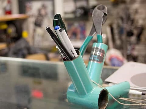 Writing pens and marker holder made from a bike frame bottom bracket on a bike repair shop bench at Bikeland.