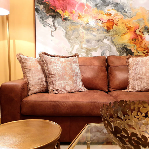 Brown sofa with naturally-dyed cushions and colourful painting in the background