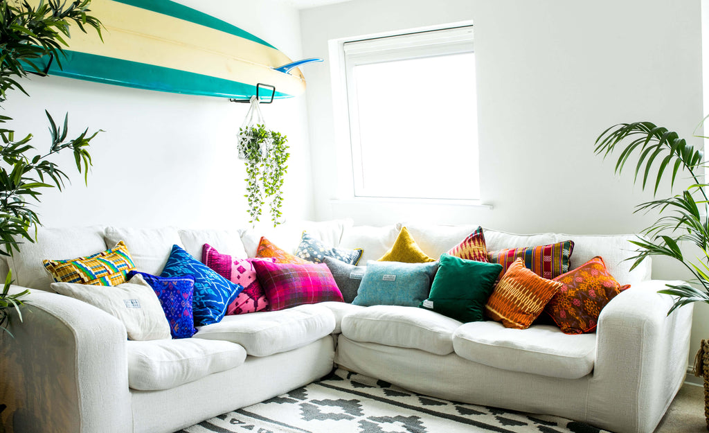 Colourful handmade cushions on an L-shaped white sofa