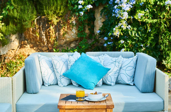 Blue and patterned white cushions on a sky-blue sofa with a wooden table in front