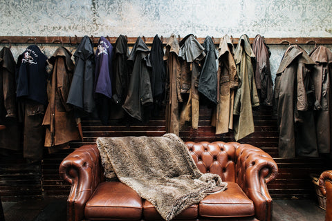 Brown leather sofa with fur throw wall of water proof coats hanging