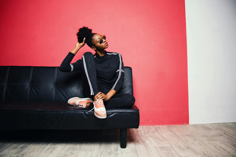 Girl sitting on black sofa, pink wall