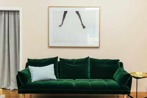 Green velvet sofa, pale cushion, image on wall